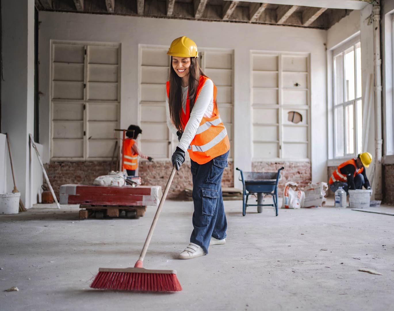 Female construction worker sweeping the floor on a construction site