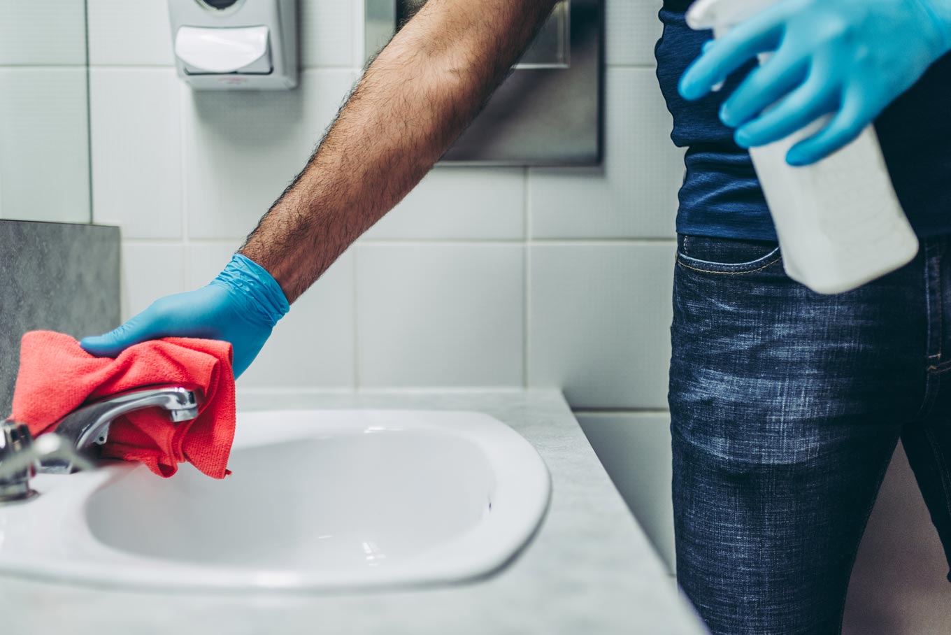 Hands of a janitor cleaning the office bathroom faucet