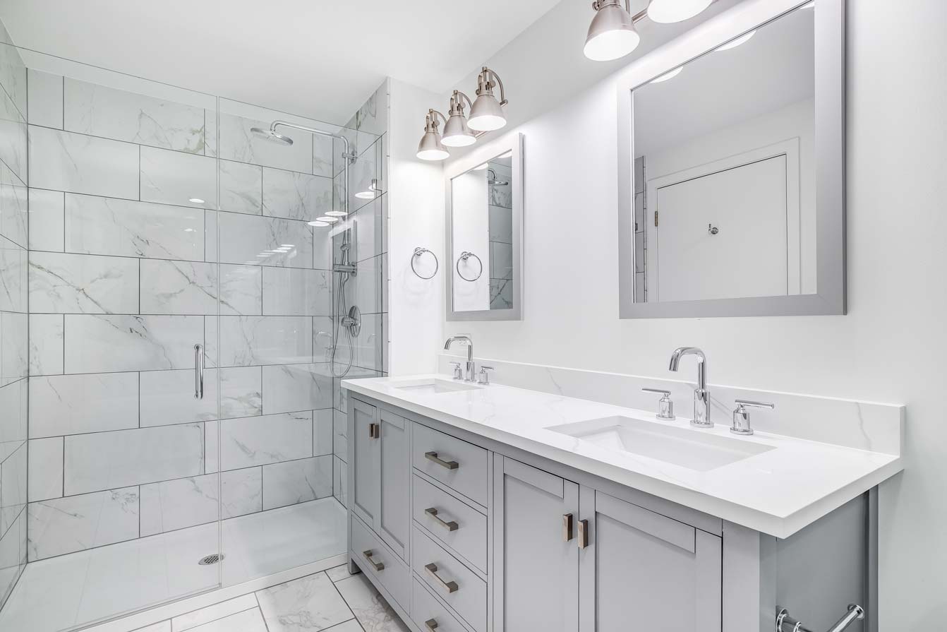 A bathroom with a grey cabinet and tiled shower